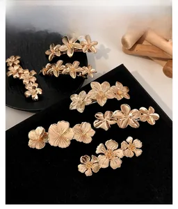 Detailed view of golden flower hair clips with brushed metal petals and textured stamens