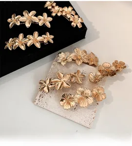 Detailed view of elegant gold floral spring hair clips on a textured stone surface