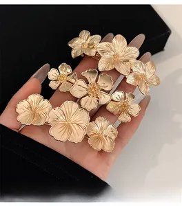 Detailed view of three gold floral metal hair clips with intricate textured petal designs