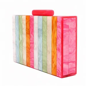 Détail d'une pochette de soirée en acrylique avec rayures marbrées et fermoir rouge