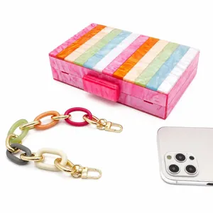 Détail d'une pochette en acrylique à rayures colorées avec chaîne en résine et smartphone