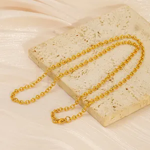 Close-up of golden O-chain necklace with lobster clasp on a beige stone platform