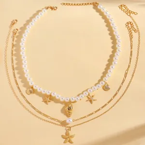 Dettaglio della collana boho a strati con ciondoli a stella marina dorata e perle