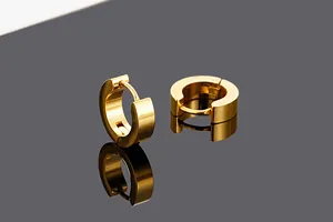 Macro view of polished gold titanium steel hoop earrings on reflective surface