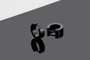 Macro view of black titanium steel hoop earrings on reflective surface for unisex style