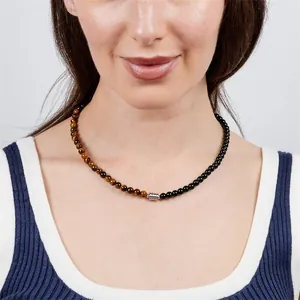 Close-up view of a 6mm tiger eye and black obsidian beaded necklace worn by a model