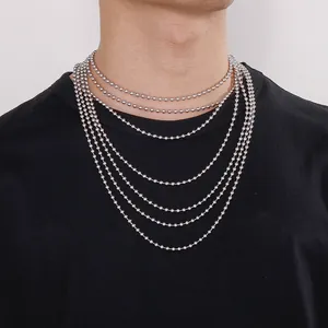 Multiple lengths of stainless steel ball chain necklaces layered on a black t-shirt