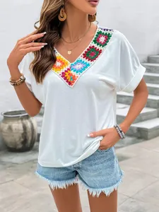 Détail du patchwork au crochet coloré sur le haut bohème blanc à col en V doux