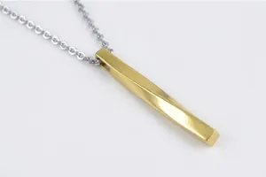 Detailed macro view of the twisted geometric gold bar pendant on a silver metal chain