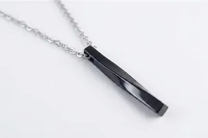 Macro view of black twisted long bar pendant with silver O-chain on wooden background