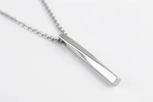 Macro detail of silver titanium steel long twisted bar pendant on dark wood background