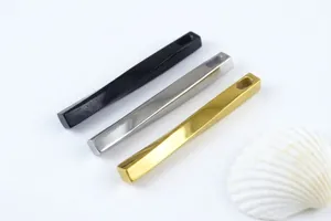 Macro shot of long geometric pillar pendants in black, silver, and gold polished titanium steel