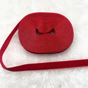 Close-up of deep red velvet ribbon roll on white faux fur background for DIY crafts