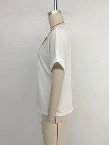 Détail de broderie florale colorée sur haut blanc à col en V et manches retroussées