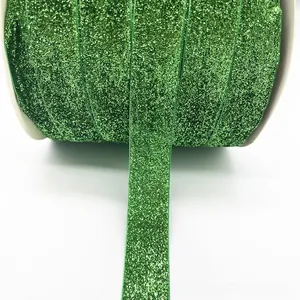 Macro shot of 1cm sparkling green glitter ribbon neatly wound on a white spool roll