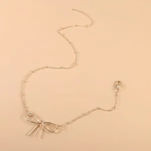 Detailed close-up of a gold bow choker with adjustable lobster clasp on beige background
