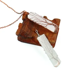 Détail de pendentifs en sélénite avec arbre de vie enroulé de fils de cuivre et d'argent