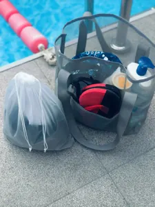 Close-up of a large grey mesh beach bag and drawstring pouch with poolside swimming gear