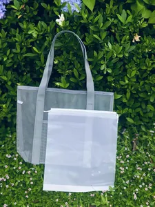 Outdoor setup of grey mesh beach tote and white drawstring pouch on grass
