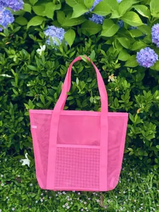 Detailed macro view of vibrant pink mesh beach bag with dual straps and outdoor pocket
