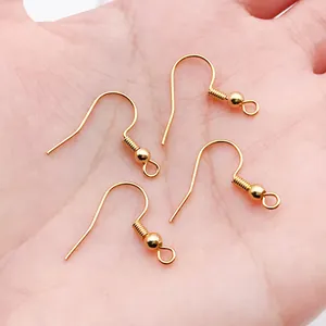 Primo piano di quattro ganci per orecchini placcati in oro con molla e perla per gioielli fai-da-te