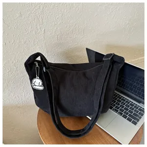 Detail of black corduroy messenger bag with vertical stripes and adjustable shoulder strap