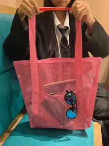 Pink mesh beach bag detail showing a front pocket holding sunglasses and reinforced handles