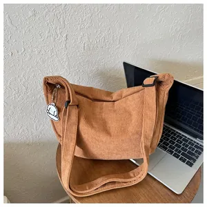Detail of brown corduroy crescent bag with cute white puppy pendant and zipper closure