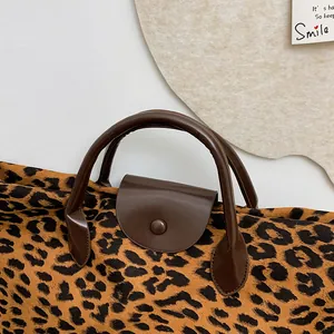 Dettaglio della borsa leopardata con manico in pelle marrone e chiusura con bottone