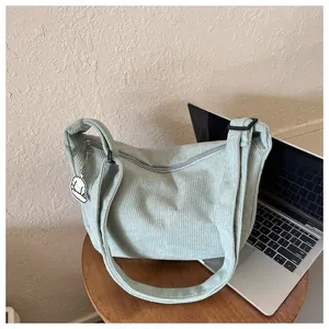 Detail of mint green corduroy hobo bag with zipper closure and cute white charm