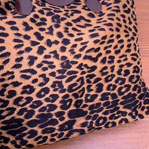 Dettaglio della trama leopardata e dei rinforzi in pelle marrone sugli attacchi dei manici