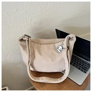 Detail of beige corduroy shoulder bag with cute puppy pendant on wooden table