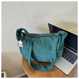 Detail view of dark green corduroy crossbody bag with cute white puppy keychain charm