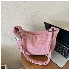Close-up of pink corduroy crescent bag with a cute cloud charm on a wooden table