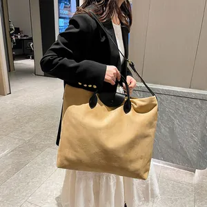 Dettaglio della borsa tote color cammello con manici neri e patta a scatto per il lavoro