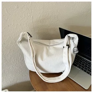 Detail of white corduroy dumpling bag with adjustable strap and cute puppy pendant