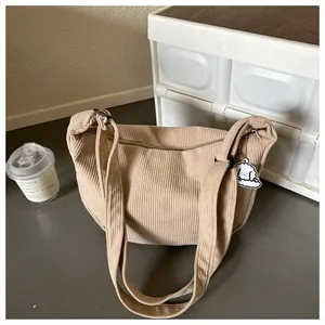 Detail of beige corduroy crescent bag with wide strap and cute cloud dog pendant