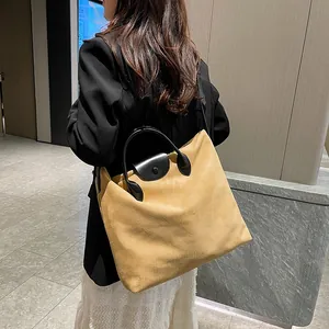 Dettaglio della grande borsa tote in pelle scamosciata kaki con manici in pelle nera