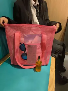 Close-up of pink mesh beach tote with reinforced handles and front pocket storage