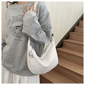 Detail of white corduroy half-moon bag with cute puppy charm accessory for women