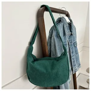 Detail of dark green corduroy crescent crossbody bag with adjustable shoulder strap