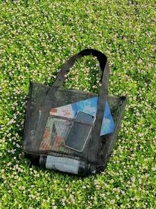 Close-up of black mesh beach bag showing a convenient front pocket for smartphone storage