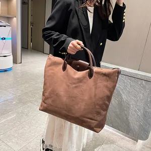 Borsa tote in camoscio marrone abbinata a blazer nero e gonna bianca in un hotel