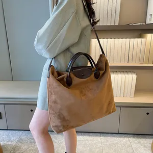 Dettaglio di una grande borsa tote in pelle scamosciata marrone con manici in pelle