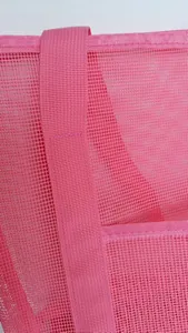 Macro detail of high-quality stitching on the wide handles of the pink mesh beach bag