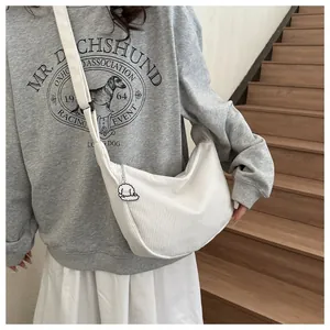 Detail view of white corduroy crossbody bag with soft vertical texture and cute dog pendant