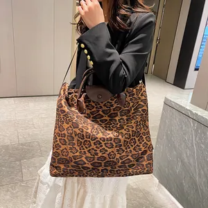 Dettaglio della grande borsa tote leopardata con manici in pelle marrone sulla modella