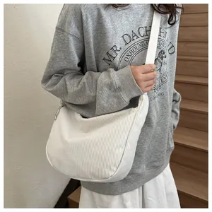 Detail of white corduroy dumpling crossbody bag featuring soft texture and zipper closure