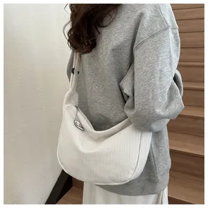 Detail of white corduroy crescent bag featuring a cute cartoon dog charm on the strap