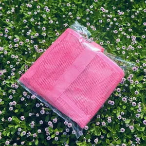 Pink mesh storage bag in transparent packaging shown on a fresh green lawn background